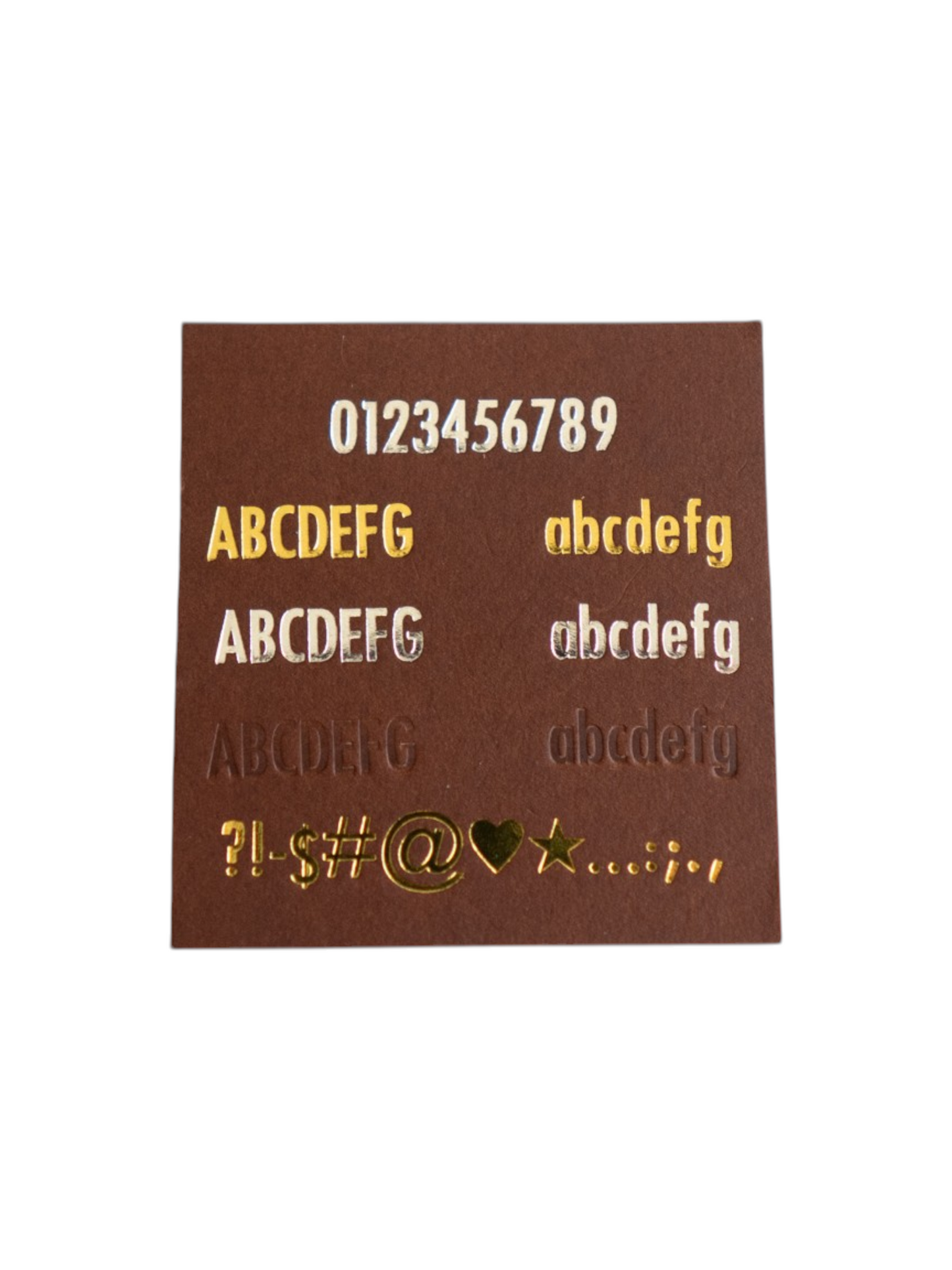 Brown card with gold embossed letters and numbers on a white background showcasing the font and character/symbol options