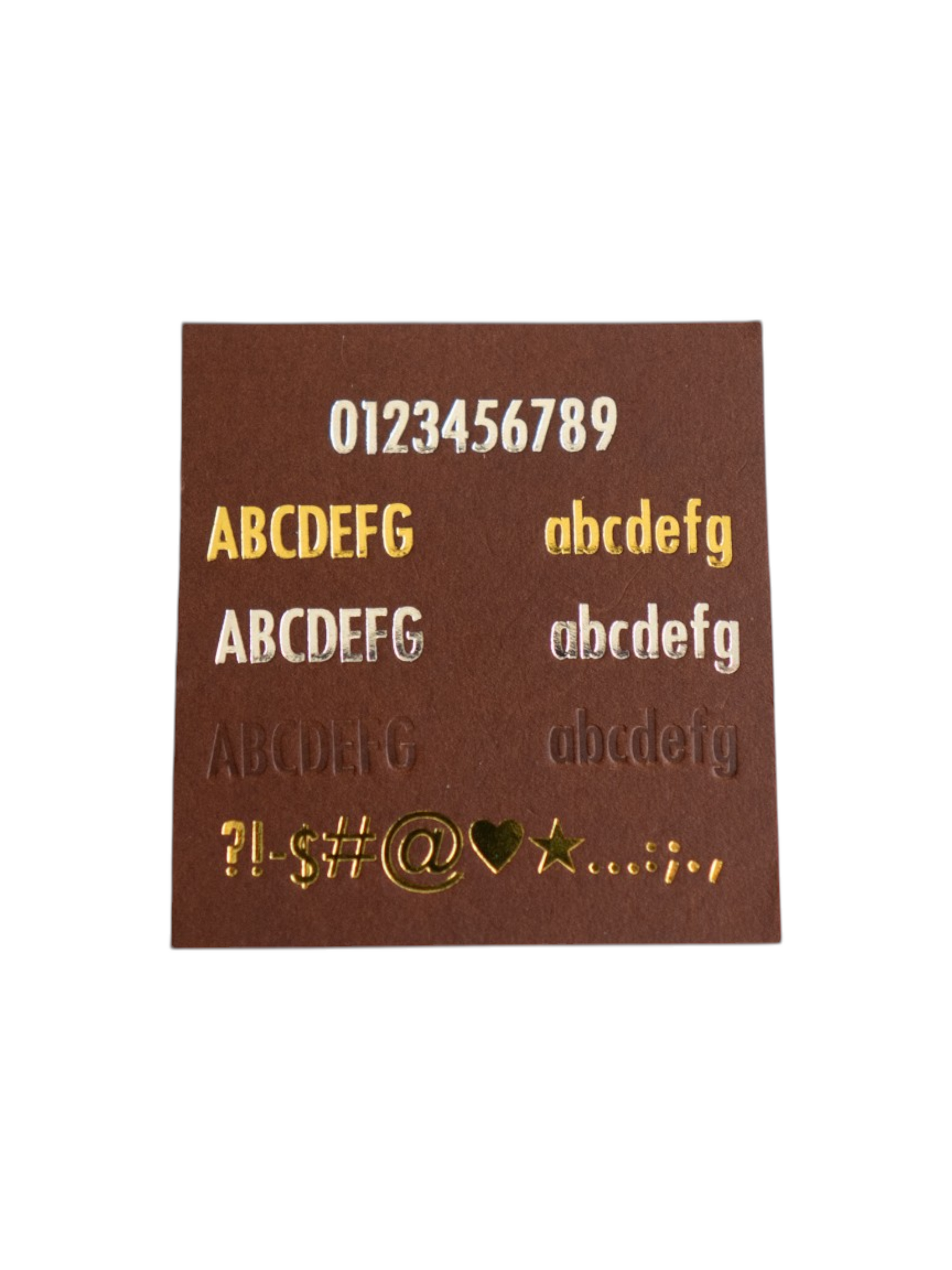 Brown card with gold embossed letters and numbers on a white background showcasing the font and character/symbol options