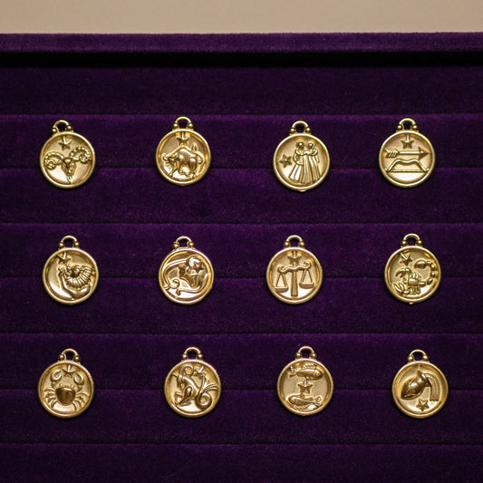 Gold zodiac pendant set on a purple display box